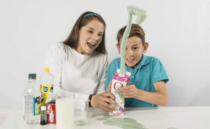 girl and boy playing with milk carton volcano